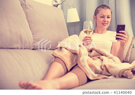 woman on sofa with wineglass and chatting on phone 41140040