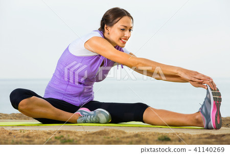 Woman doing exercises on beach by ocean Woman doing exercises on beach by ocean 41140269