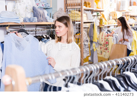 Smiling woman choosing blue sweater in the modern shop Smiling woman choosing blue sweater in the modern shop 41140273