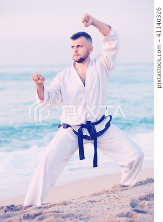 Guy doing karate poses at sunset sea shore Guy doing karate poses at sunset sea shore 41140326