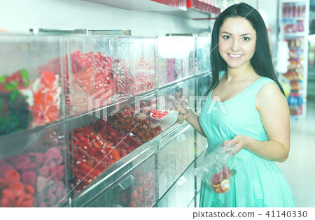 Pretty girl in sweets store picks up candies in bag Pretty girl in sweets store picks up candies in bag 41140330