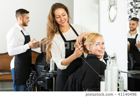 Happy hairdresser doing hairstyle Happy hairdresser doing hairstyle 41140496