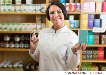 Smiling mature woman seller holding nutrients 41140606