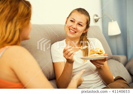 women on the sofa with plate of cake 41140653