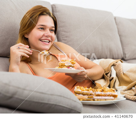 Cheerful female eating sweet cake at home Cheerful female eating sweet cake at home 41140670