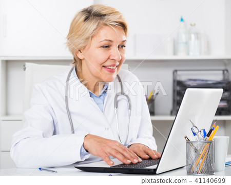 Doctor in gown waiting for patient Doctor in gown waiting for patient 41140699