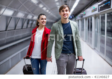 Portrait of couple with wheeled trollers at subway platform Portrait of couple with wheeled trollers at subway platform 41140827