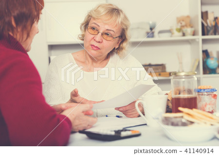Upset mature woman talking with female about papers Upset mature woman talking with female about papers 41140914