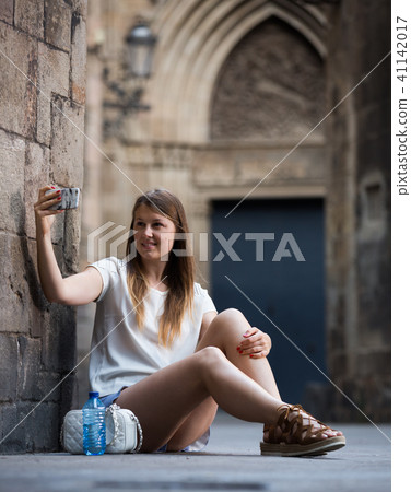 Young woman taking selfie while sitting nea stone wall Young woman taking selfie while sitting nea stone wall 41142017