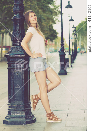 Woman resting against lamp post on street 41142102