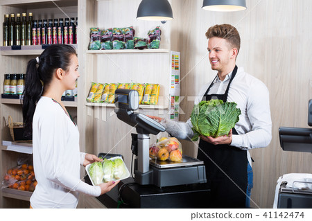 Seller assisting customer to weigh purchases 41142474