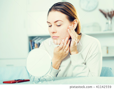 Young woman is satisfied of quality her skin in with mirror 41142559