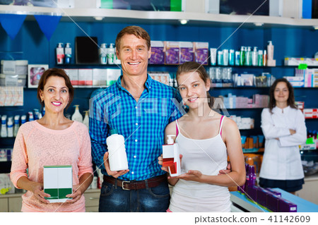 Smiling parents with girl teenager holding drug store goods 41142609