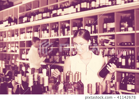 Young woman choosing bottle in wine shop 41142678