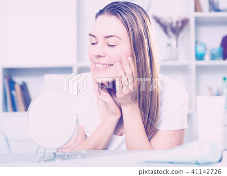 Young woman is satisfied of quality her skin in with mirror 41142726