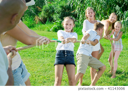 Cheerful kids with parents playing tug of war Cheerful kids with parents playing tug of war 41143006