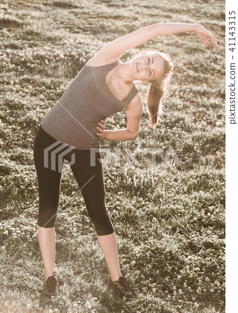 woman in sportwear doing exercises on mat in the garden woman in sportwear doing exercises on mat in the garden 41143315