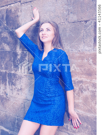 Elegant girl is posing in blue dress near old wall Elegant girl is posing in blue dress near old wall 41143566
