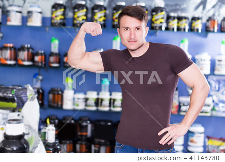 Young sportman demonstrating muscles in sport nutrition store 41143780