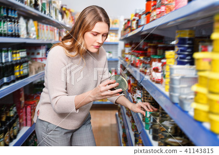 Woman customer holding canned fish goods in the food store 41143815