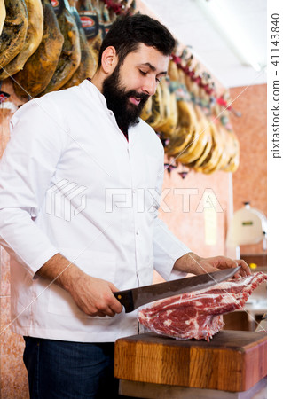 Male shop assistant carving meat Male shop assistant carving meat 41143840