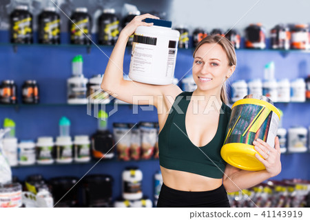 sporty woman holding big cans of sport nutrition 41143919