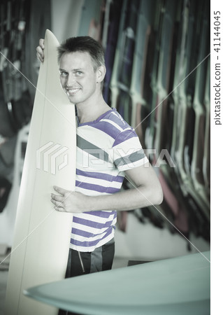 Portrait of positive guy who is buying surfboard 41144045