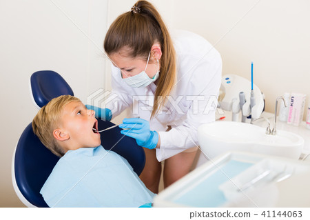 Stomatologist in uniform is taking visional inspection of a teenager on the chair 41144063