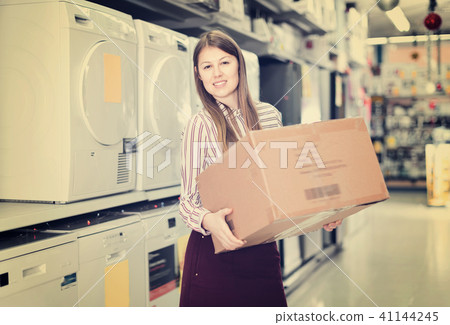 Female housewife happy from buyings in home appliance store, standing with big box Female housewife happy from buyings in home appliance store, standing with big box 41144245