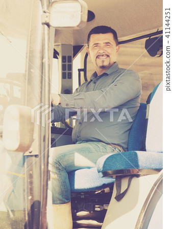 Cheerful farmer sitting in big tractor 41144251