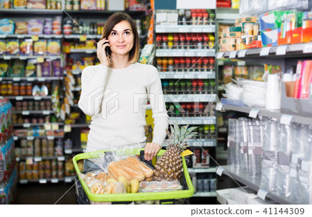woman consulting on phone about shopping in supermarket woman consulting on phone about shopping in supermarket 41144309