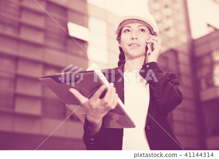 Female designer in suit and hat is talking about project by the phone Female designer in suit and hat is talking about project by the phone 41144314