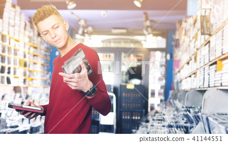 Male looking CD and DVD in shop attentively reading contents Male looking CD and DVD in shop attentively reading contents 41144551