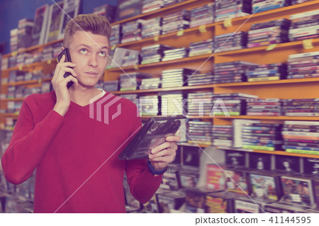 Smiling guy talking on mobile phone in shop 41144595