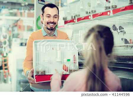 Male shop seller offering cage with canary bird 41144596