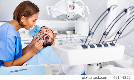 Stomatologist girl in uniform is taking visional inspection of a man 41144832