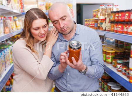 Family couple in store holding preserved jar in grocery section 41144833