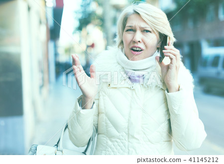 Female in the city in scarf and jacket talking on phone Female in the city in scarf and jacket talking on phone 41145212