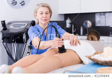 Beautician performing machine cosmetological procedure Beautician performing machine cosmetological procedure 41145644