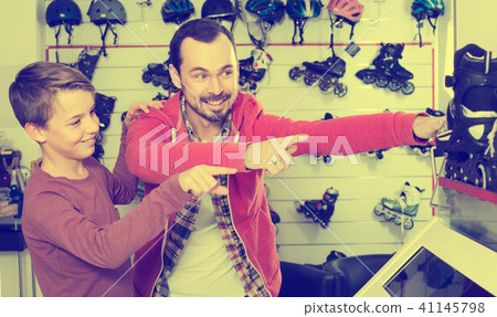 father and son deciding on new roller-skates in sports store 41145798