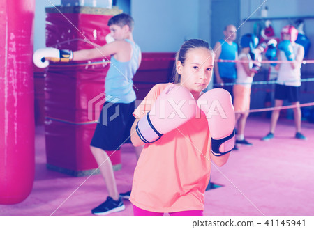 Girl in gloves posing during boxing training at gym Girl in gloves posing during boxing training at gym 41145941