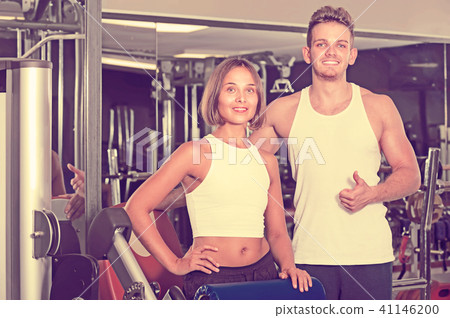slim young man and woman taking pause between exercising in gym slim young man and woman taking pause between exercising in gym 41146200