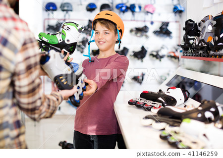 Positive male demonstrating roller-skates to boy Positive male demonstrating roller-skates to boy 41146259