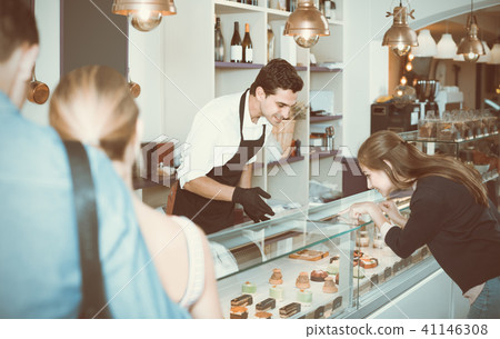 Friends are choosing delicious cakes from showcase Friends are choosing delicious cakes from showcase 41146308