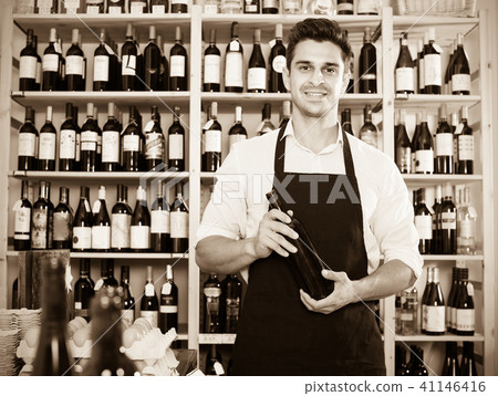 man seller holding bottle of wine in shop . 41146416