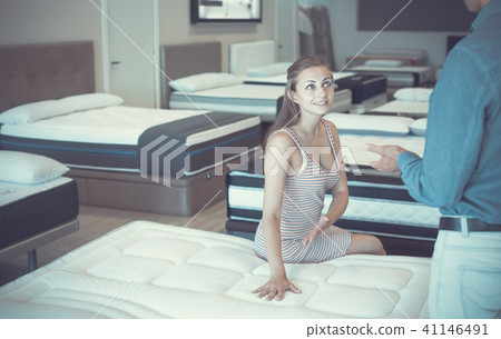 Smiling girl choosing mattresses and sitting 41146491