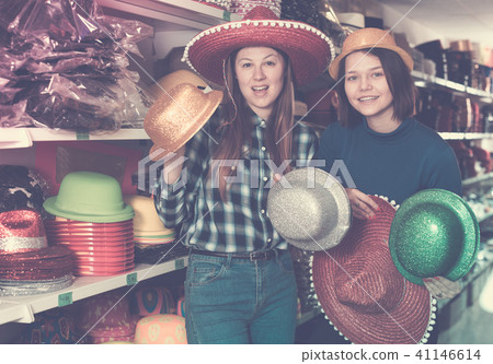 Female friends choosing funny headdresses in store Female friends choosing funny headdresses in store 41146614