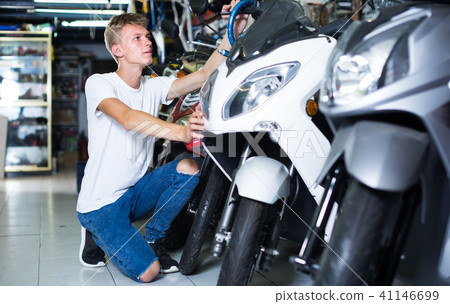 concentrated man motorcyclist choosing the bike in the shop concentrated man motorcyclist choosing the bike in the shop 41146699