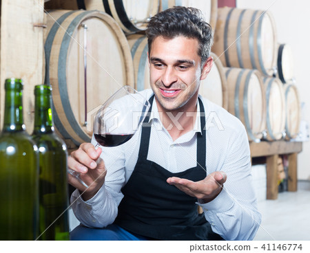male seller holding glass on wine in cellar . 41146774