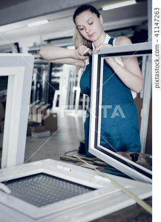 Workwoman assembling PVC window in workshop with manual tools Workwoman assembling PVC window in workshop with manual tools 41147263